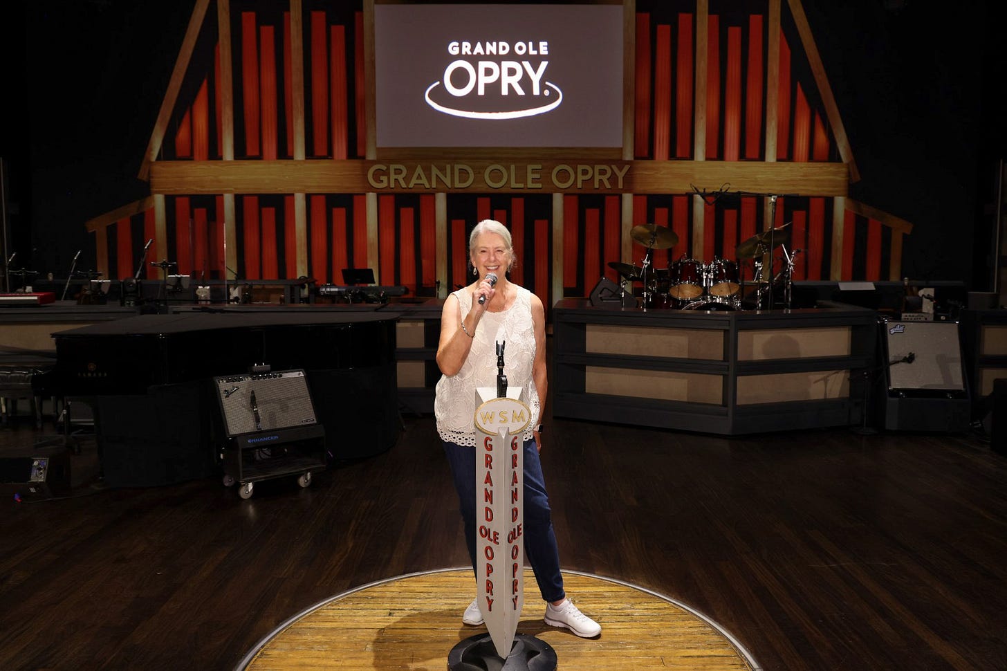 Photo of the author standing  with the microphone in hand in the wooden circle on the stage of the Grand Ole Opry in Nashville Tennessee