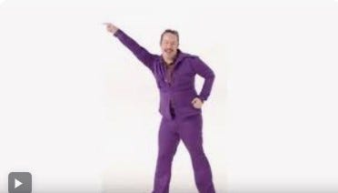 Man in purple leisure suit begins to do the dance the hustle