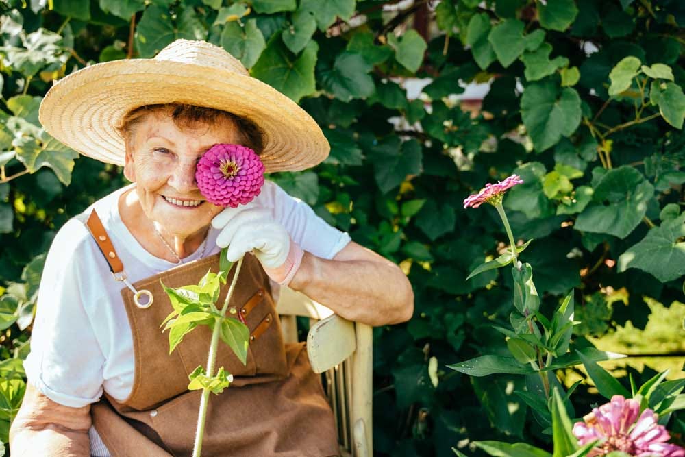 Positive elder woman enjoying time in her garden.