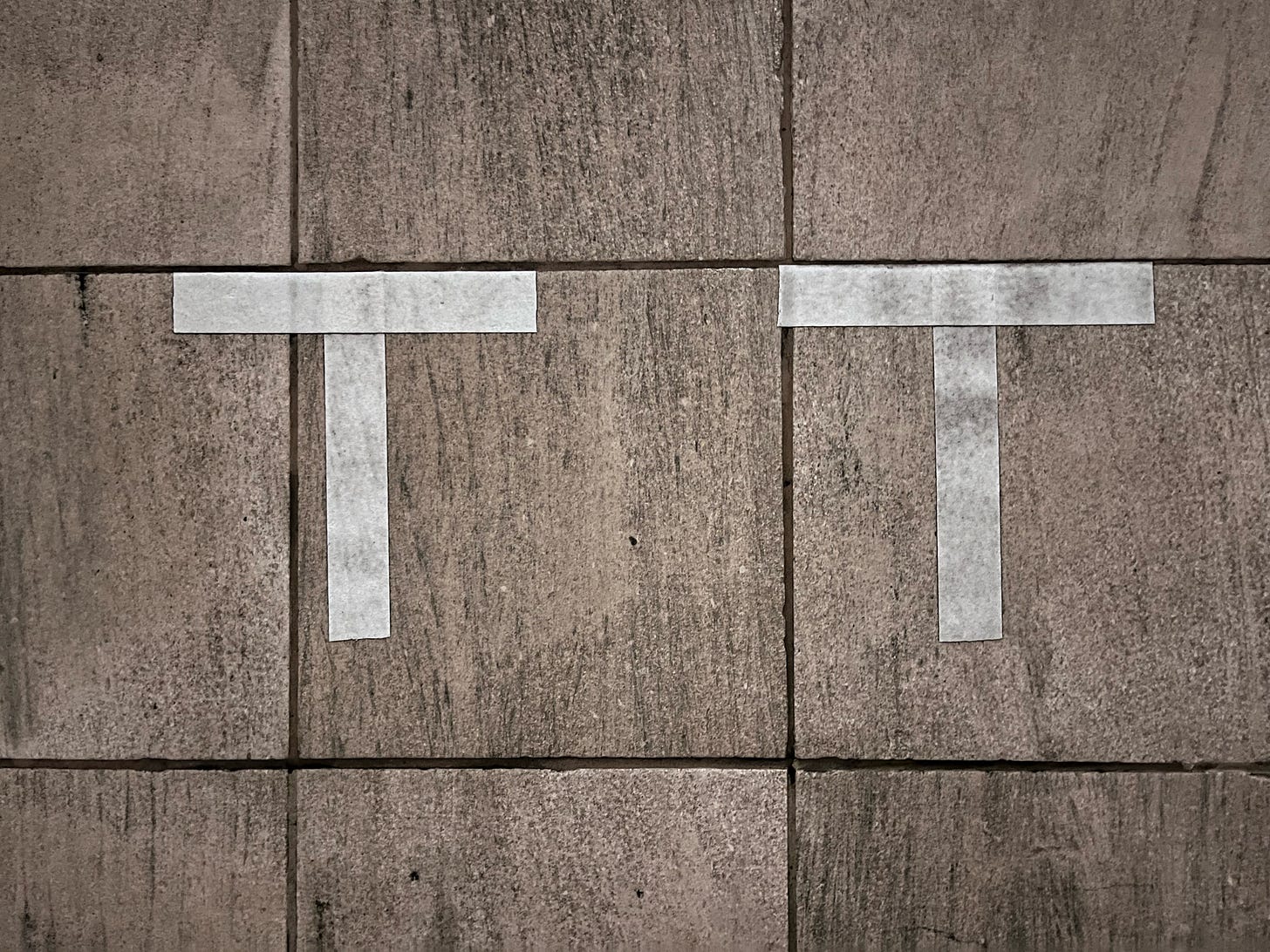 two letter Ts in white against a tiled background