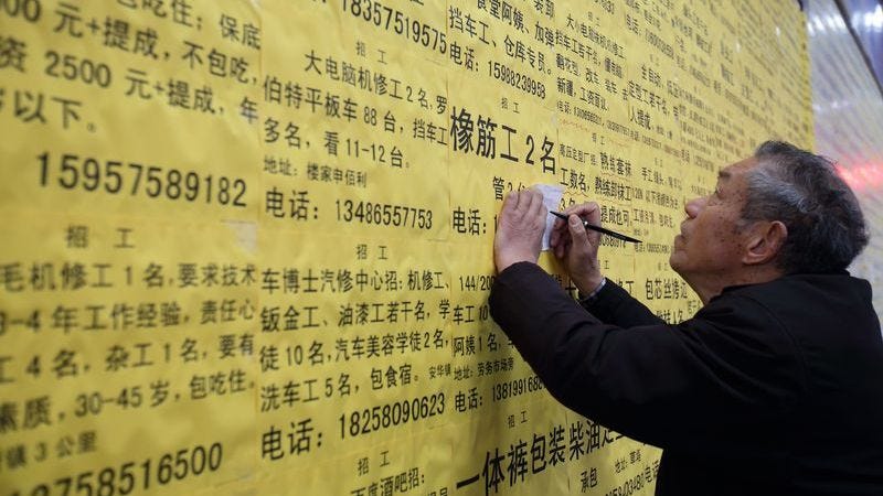 Elderly Chinese migrant worker looking at job ads on a wall