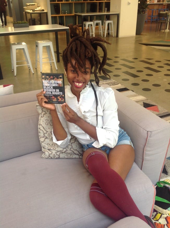 Director Nevline Nnaji smiling and holding a copy of her film, Reflections Unheard Black Women in Civil Rights