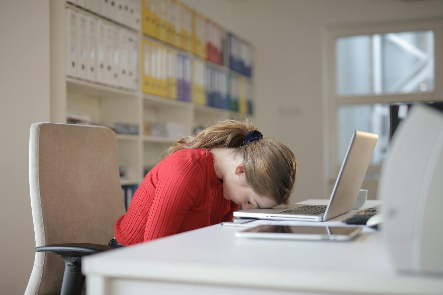 Photo of woman at desk with her head down on the keyboard