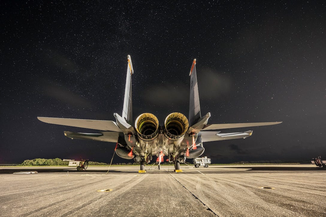 An aircraft is parked on a tarmac under a starry sky.