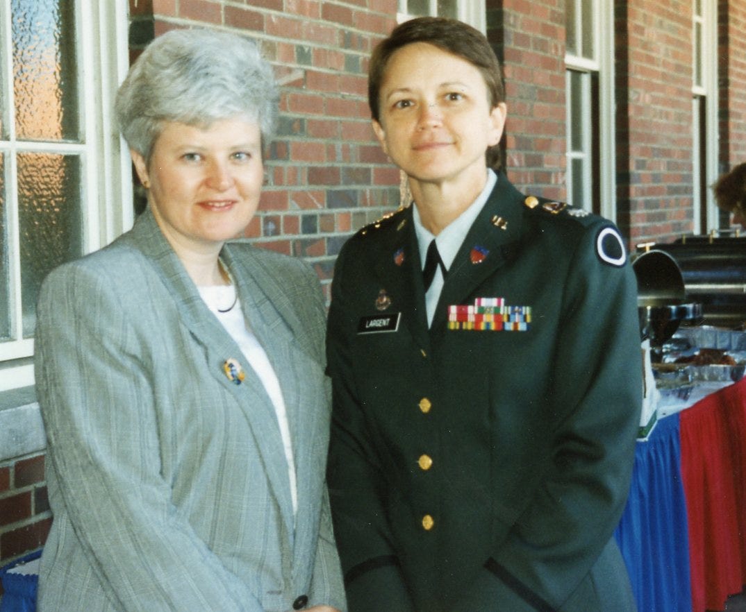 Two women, one with white hair wearing a dress suite and one with sort brown hair in an Army dress uniform
