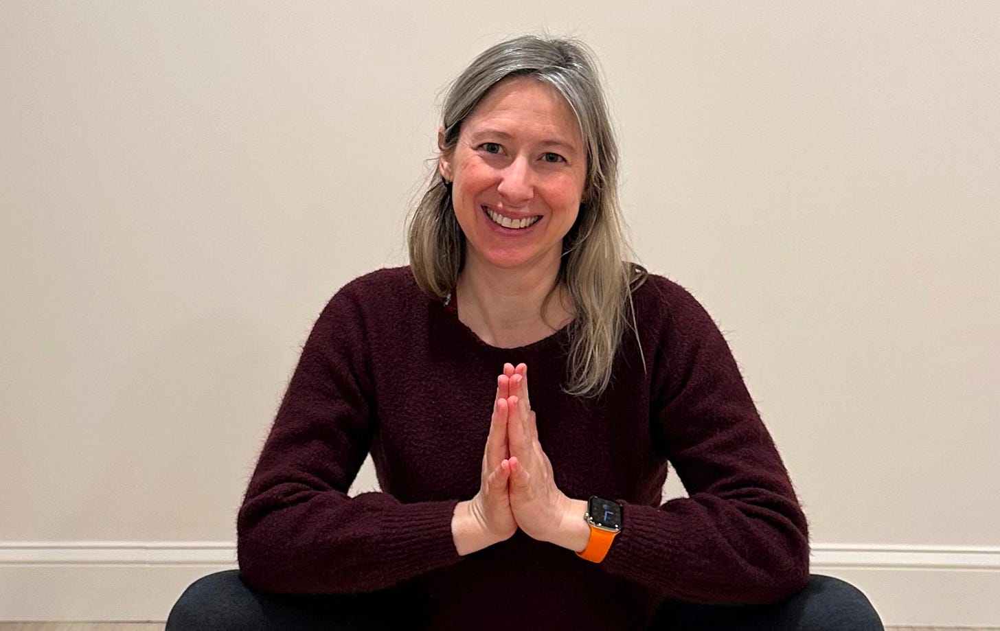 Woman smiling at camera with hands at heart center