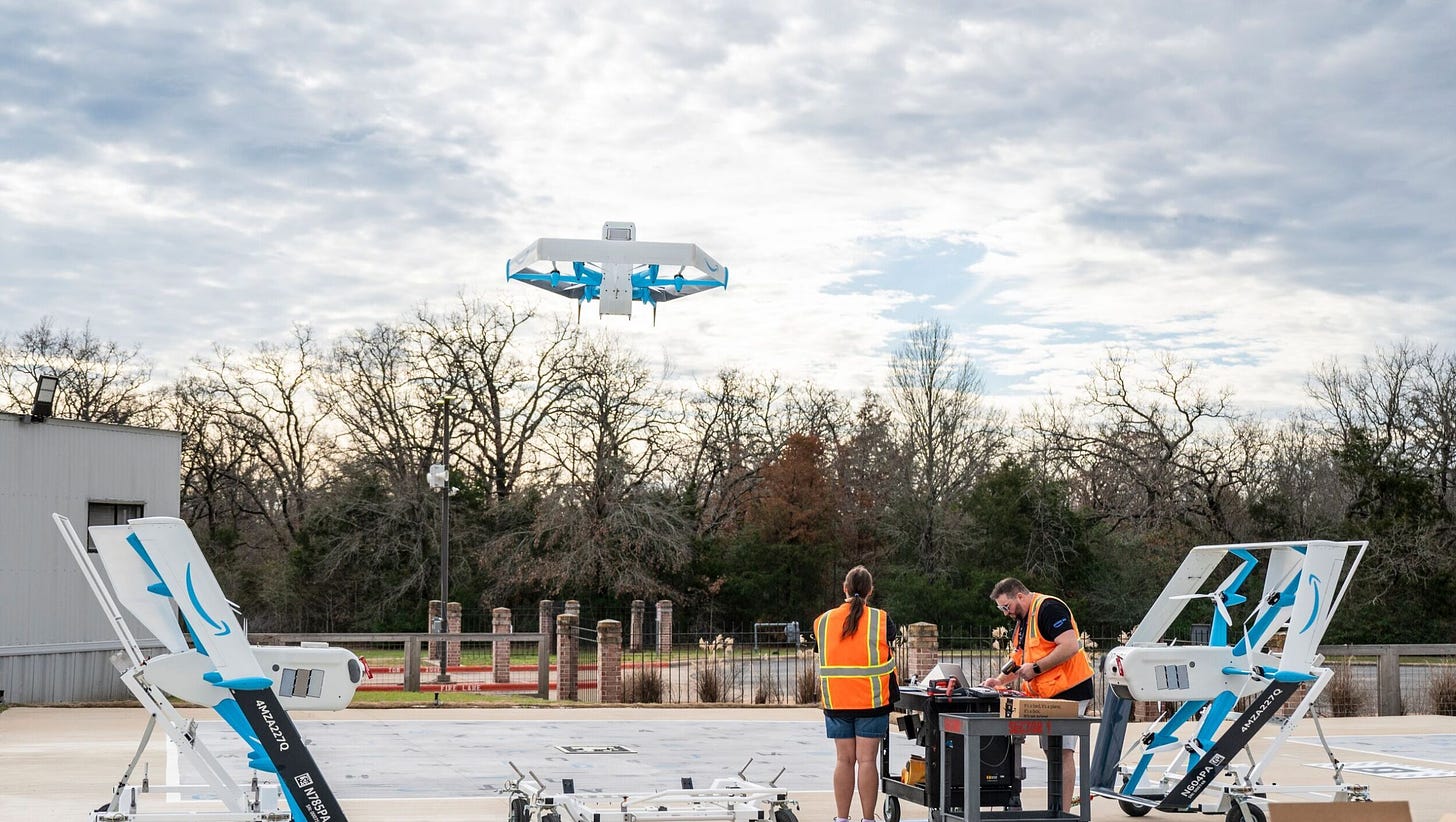 An image of two employees standing on a launch pad helping monitor and operate a drone that is taking flight.