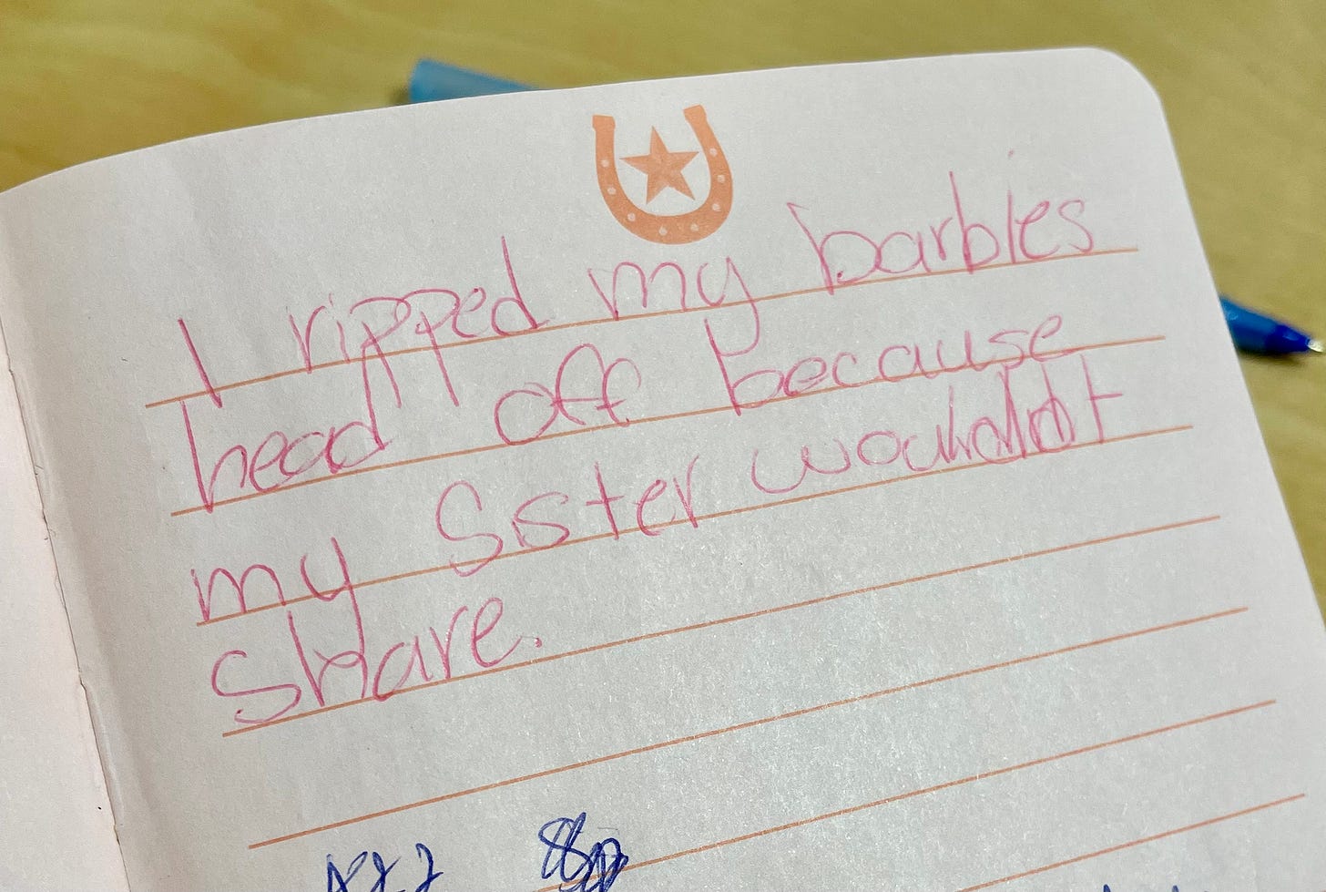photo of handwriting in a little girl's journal that says "I ripped my Barbie's head off because my sister wouldn't share."