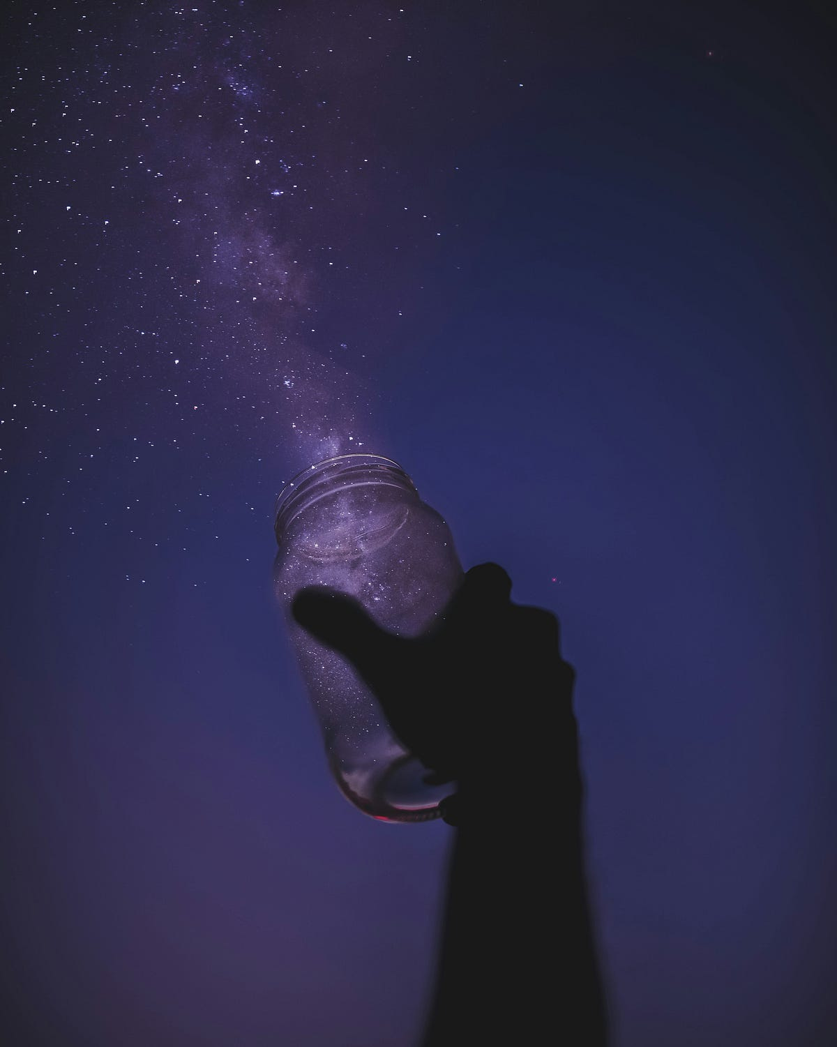 A hand holds an open jar in the night