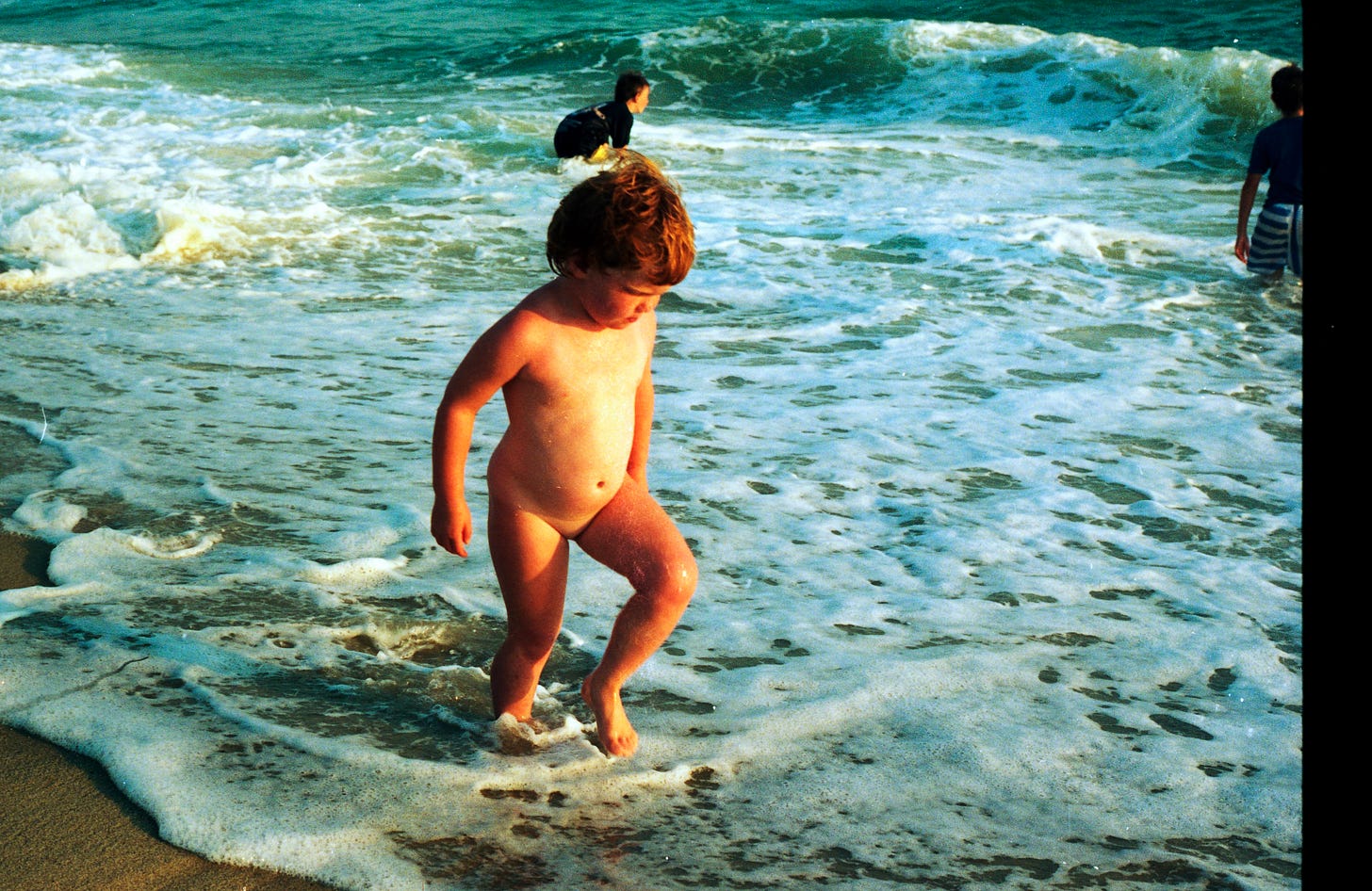 Me, naked, age 3, standing in the surf at Red Barn. My brothers are visible in the background.