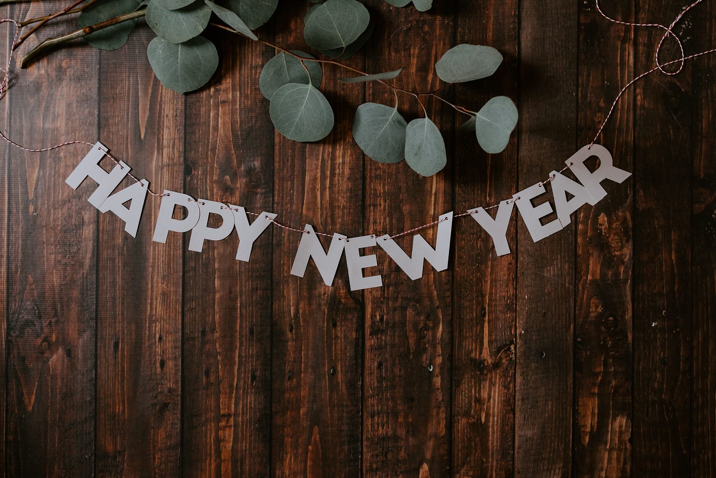 Banner reading "Happy new year" strung across a wood panelled wall with some ivy above.