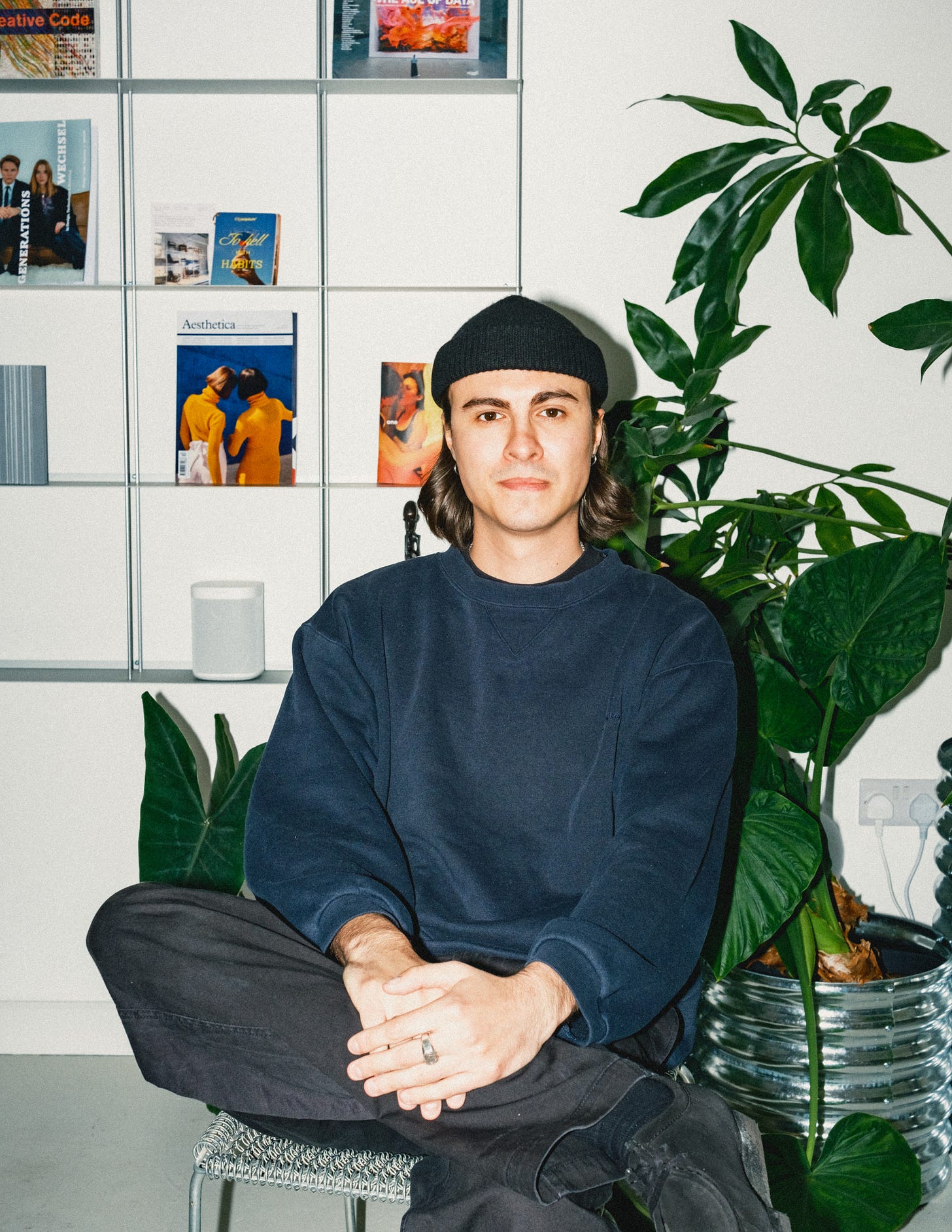 Photograph of a young man sitting in a chair in a creative studio