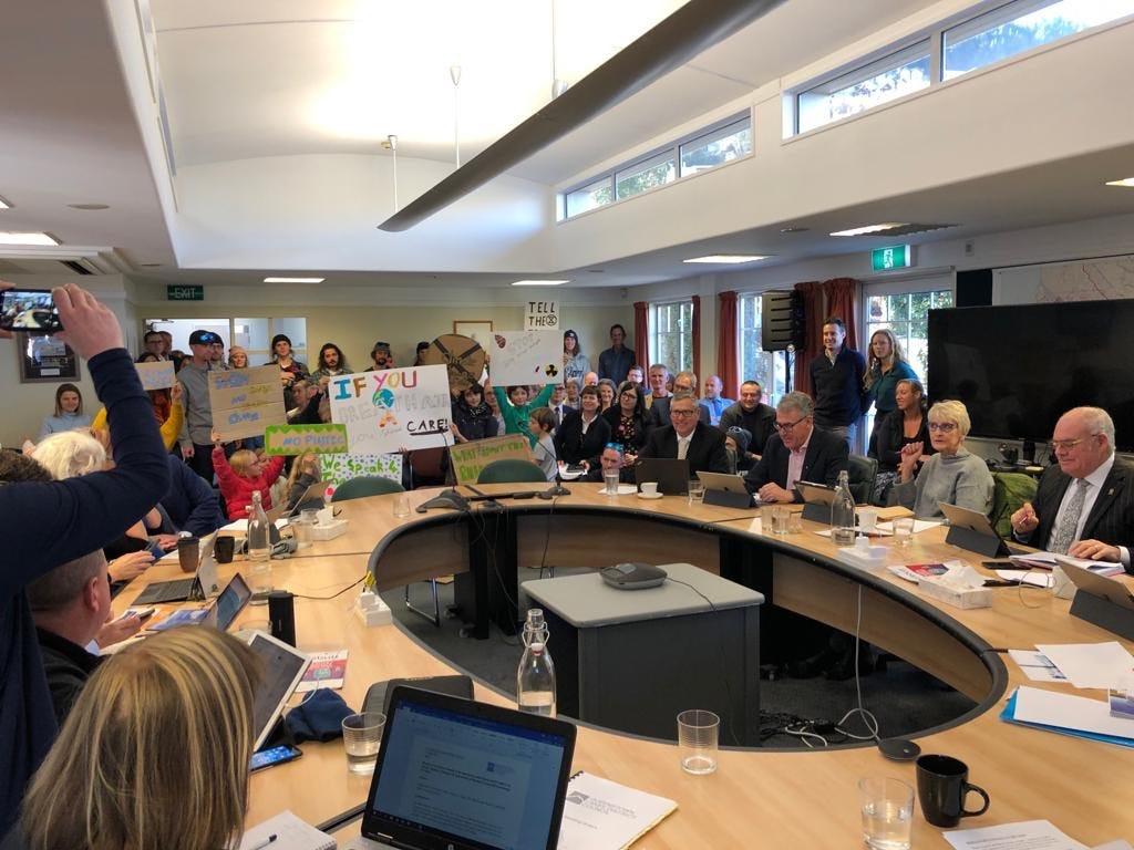 Extinction Rebellion group at Queenstown local council meeting holding signs
