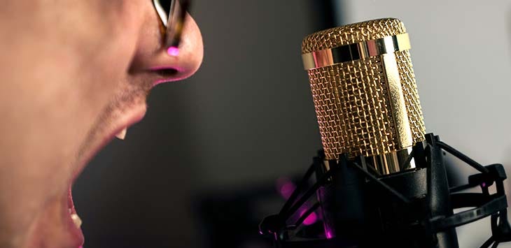 Photo of a man shouting into a microphone.