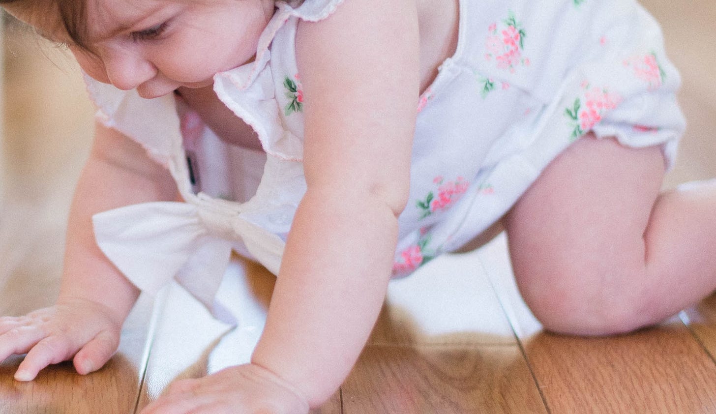 baby girl crawling on wood floor with pudgy wrists and knees