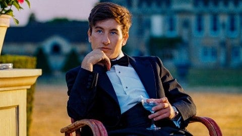 Image of actor Barry Keoghan in a tuxedo with a drink in his haind, looking contemplative.