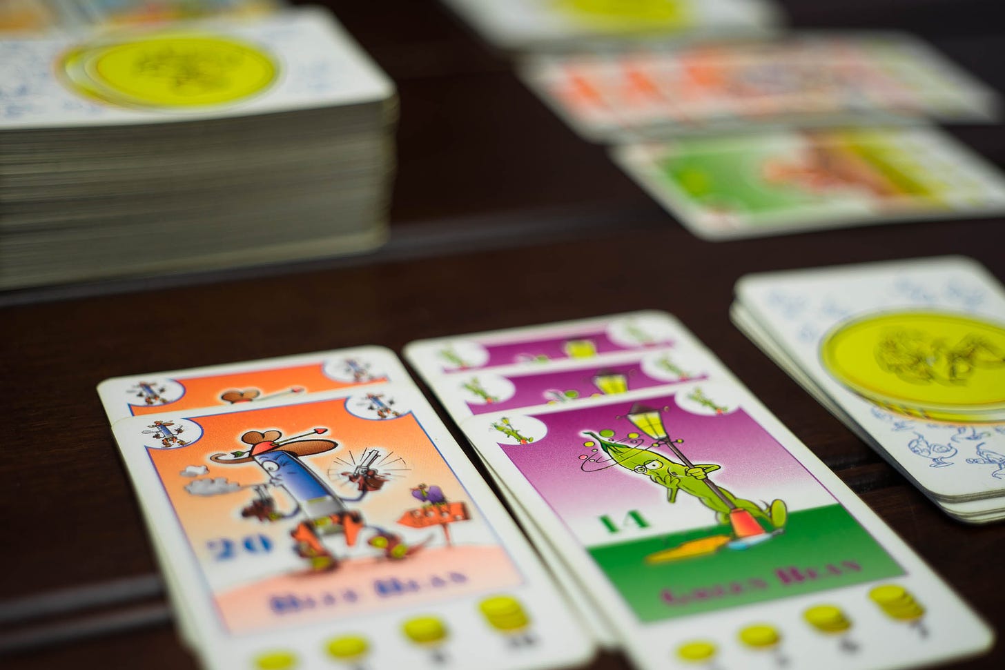Cards from the game Bohnanza on a table. There are two planted fields, one with Blue Beans and one with Green Beans.