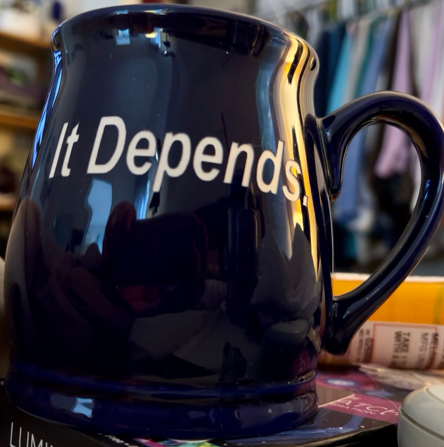 A dark blue coffee mug with the words “It Depends” written on it in a typeface.