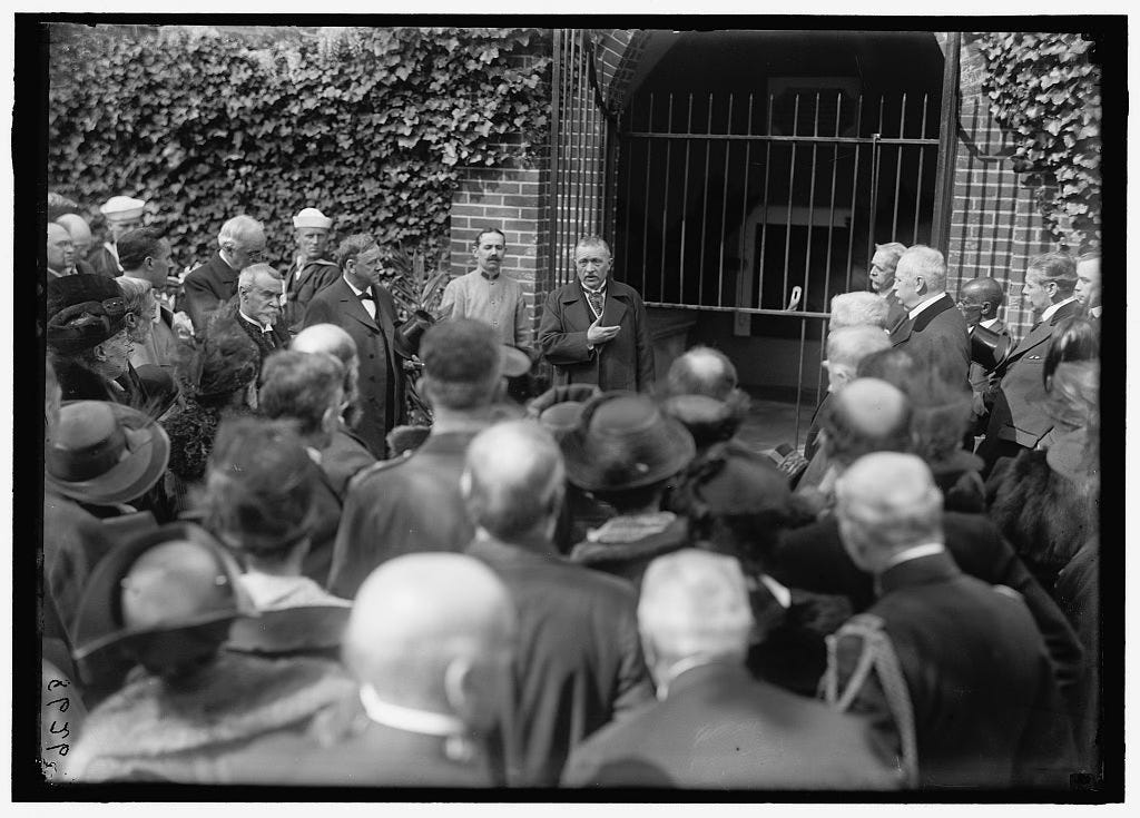 Photo of Harrison Dodge in front of the opened tomb of George Washington with a crowd of visitors looking