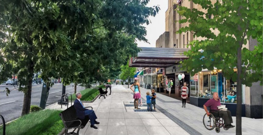 Drawing of the future look of the west sidewalk of Connecticut Avenue standing in front of the post office and looking south. The Uptown and Transcendence storefronts are visible on the right. On the left, are benches facing storefronts, four trees providing shade, and green sidewalk space. Drawings of people are seen, including children, a gentleman in a wheelchair with books, and a woman with balloons. The sidewalk looks new and clean, with the right side gray and the left side cream.  