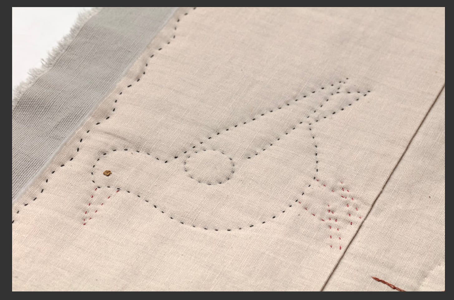 A stitched bird on cream fabric, the stitching outlines the image with no colour within.