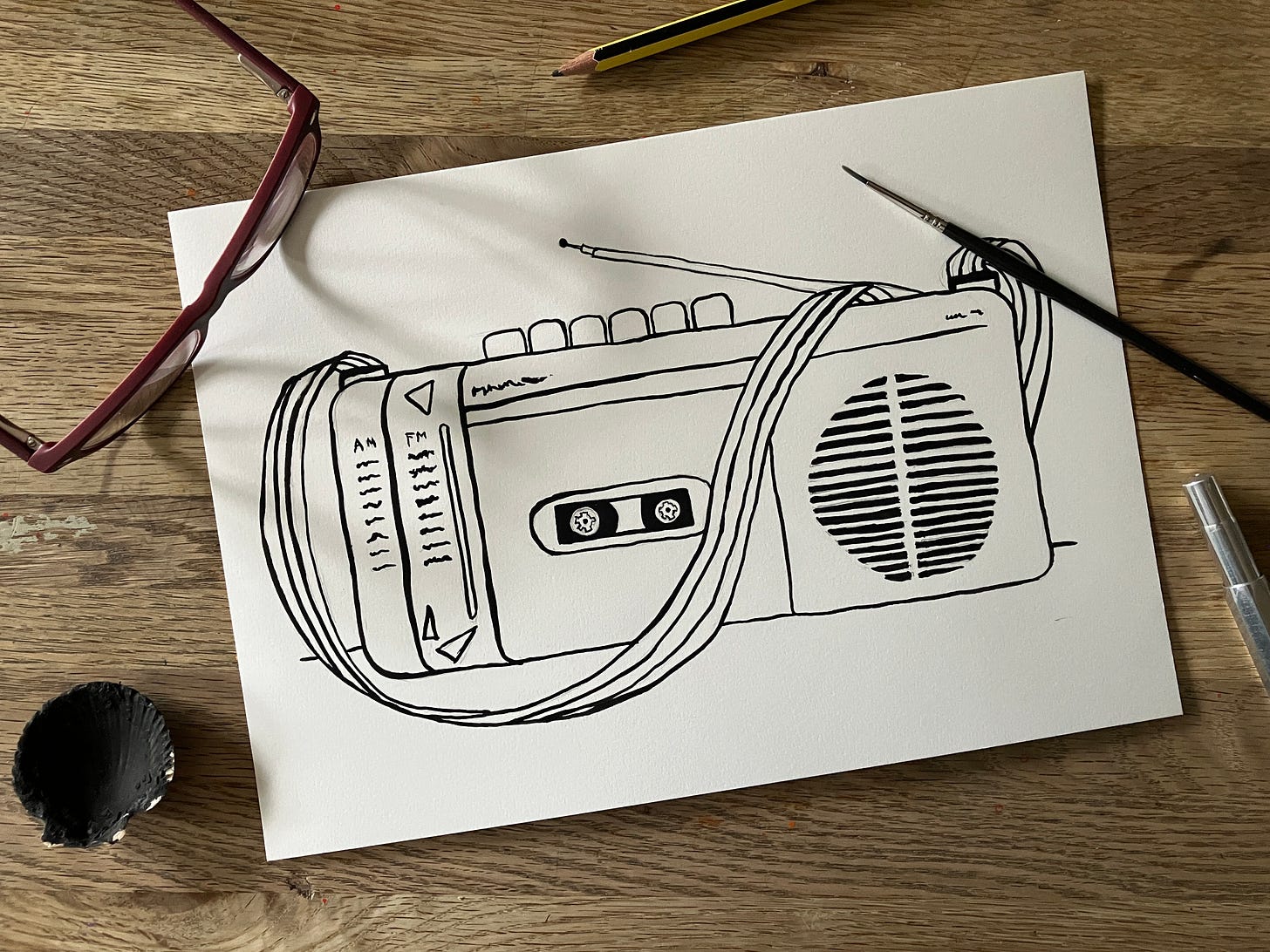 Painted picture of a retro tape player sits atop a wooden table surrounded by spectacles and pens and pencils