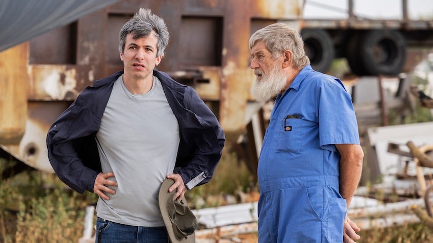 Two man stand next to each other, one middle aged and exasperated, the other old and confident. Two man stand next to each other, one middle aged and exasperated, the other old and confident.