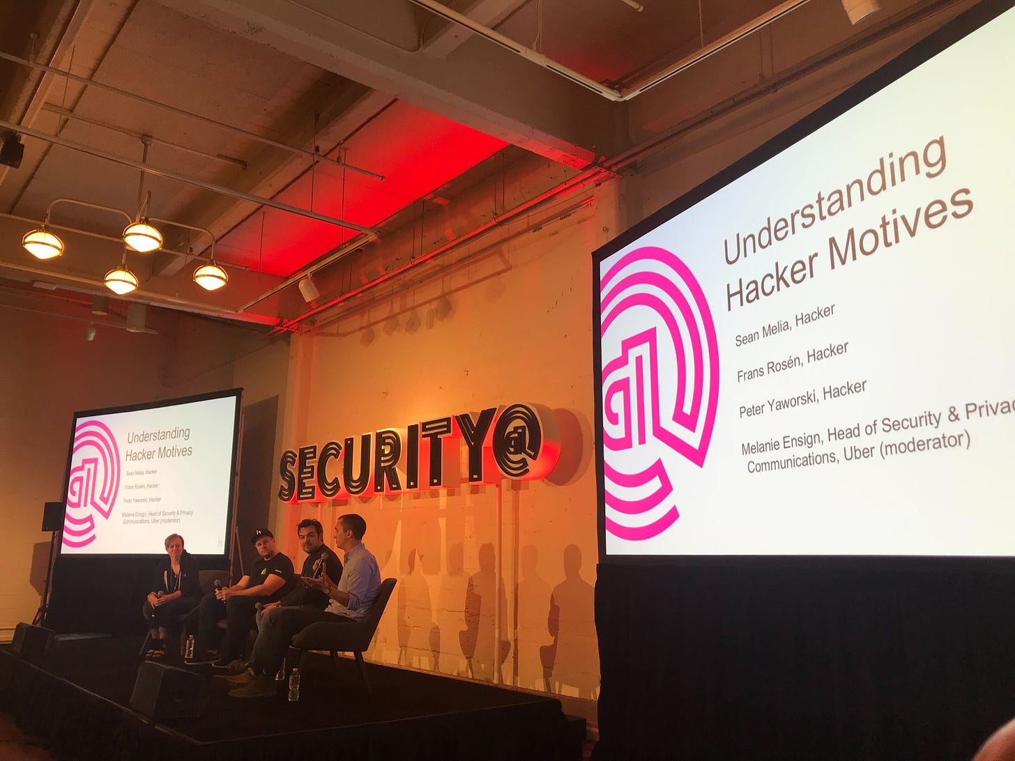 Picture from a security conference in which panelists sit in front of a sign that says "Security."