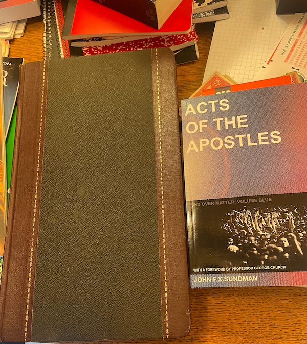photo of a leather-bound journal with a plain cover. It sits on a cluttered table next to a paperback copy of my book Acts of the Apostles, which I put there for scale. The journal is 8.5 inches wide by 14" tall.