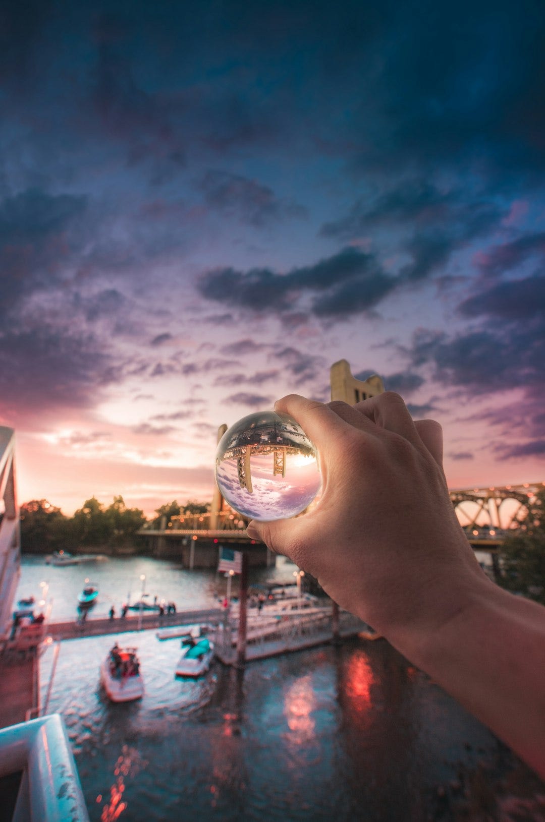 person holding crystal with reflected boat