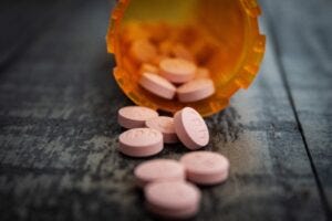 pink pills spilling out a pill bottle