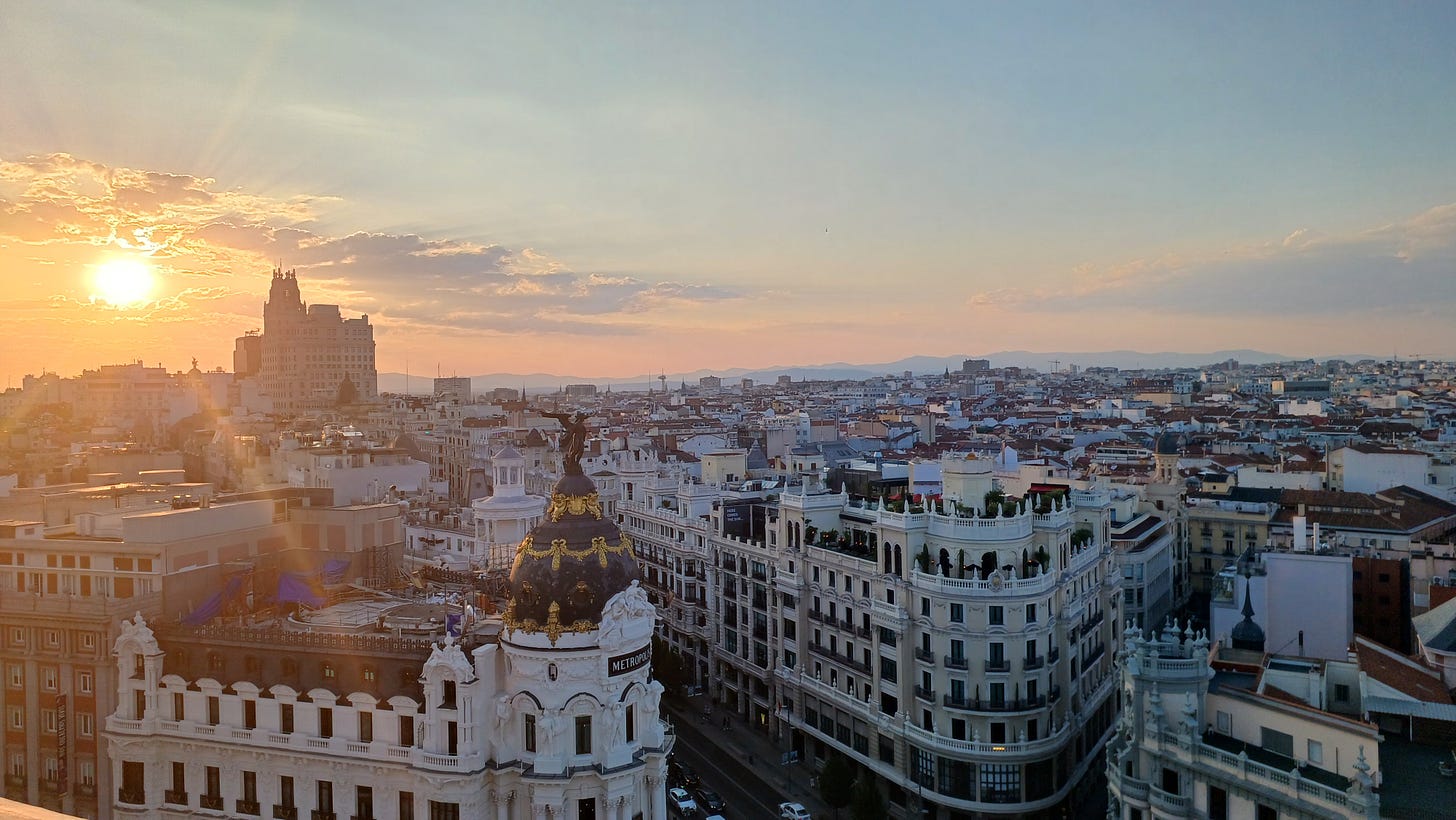 La luce del tramonto arriva da sinistra e illumina con raggi rosati il tetto e la cupula grigia e oro dell'hotel Metropolitan.