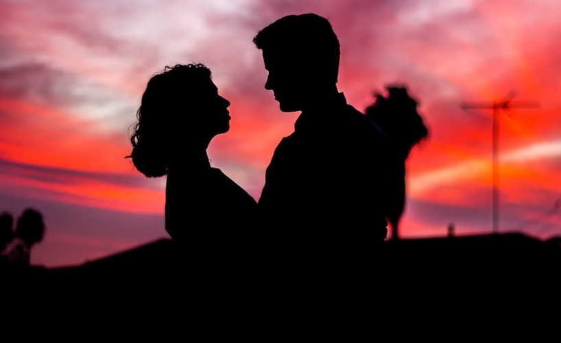 silhouette of man and woman facing each other during golden hour