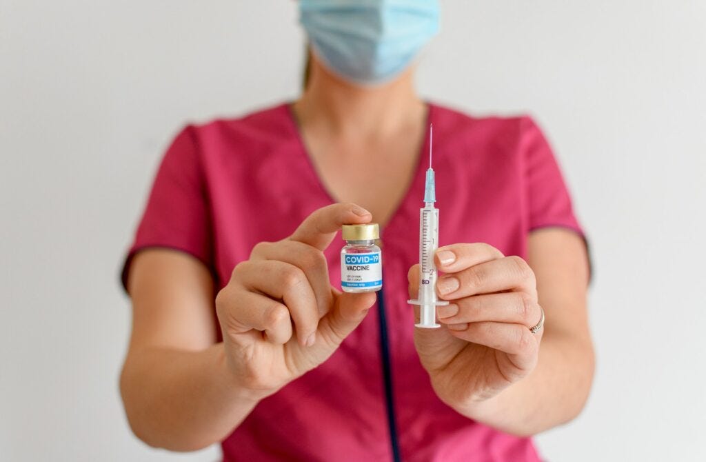 Selective focus closeup image of person holding covid vaccine vials and syringe.