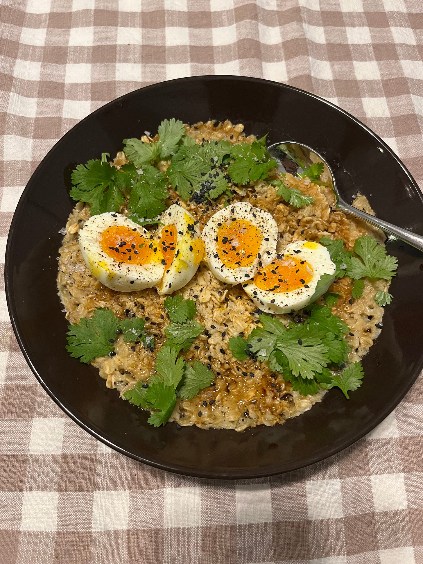 bowl of oatmeal with cilantro, eggs, and sesame seeds