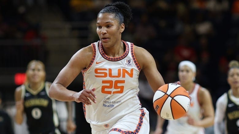 A female basketball player wearing number 25 dribbles the ball with her left hand while running up the court.