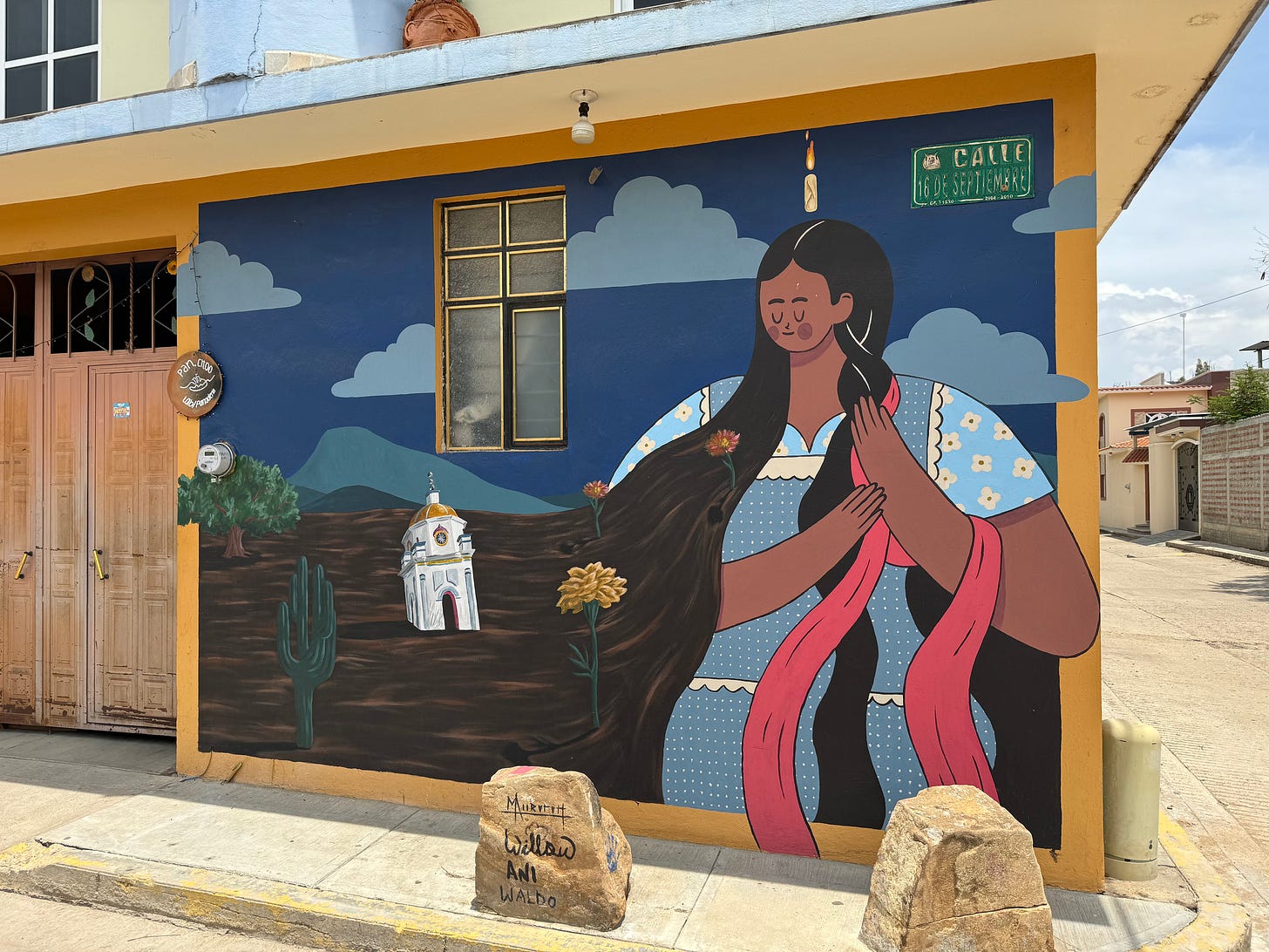 A mural of a woman brushing her hair, which as it flows toward the ground becomes the soil.