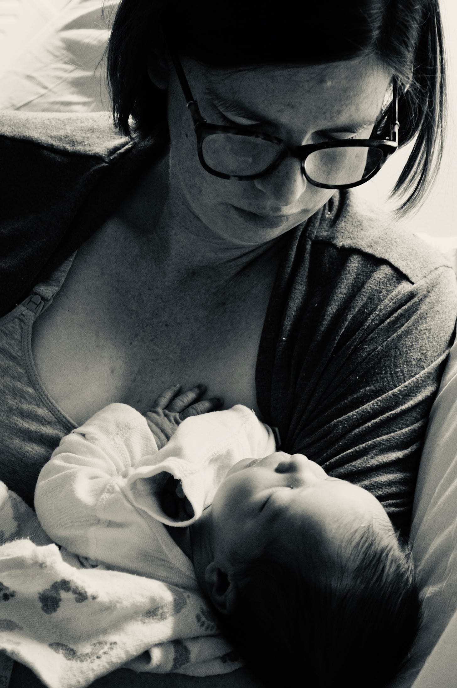 woman wearing glasses holding newborn