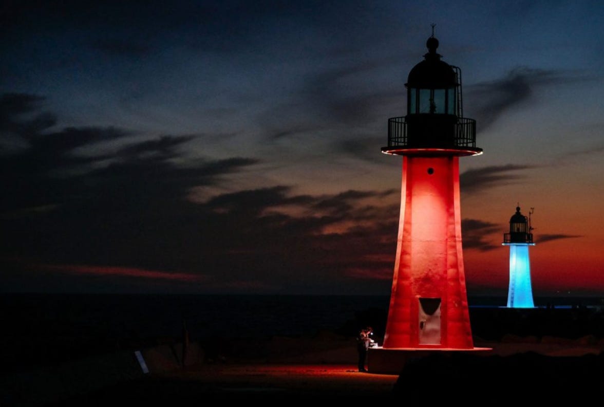 Two lighthouses in the night, one with red light, one with blue light