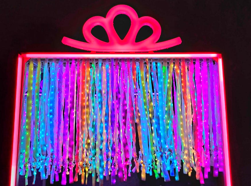 A large illuminated gift, in the form of a walk-through rainbow curtain of light