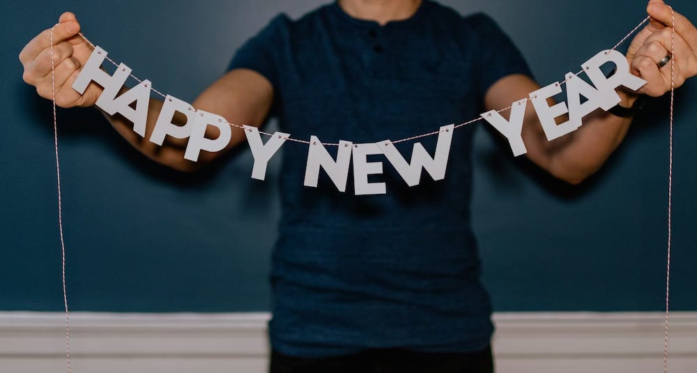 A man holding a string decoration that spells out HAPPY NEW YEAR