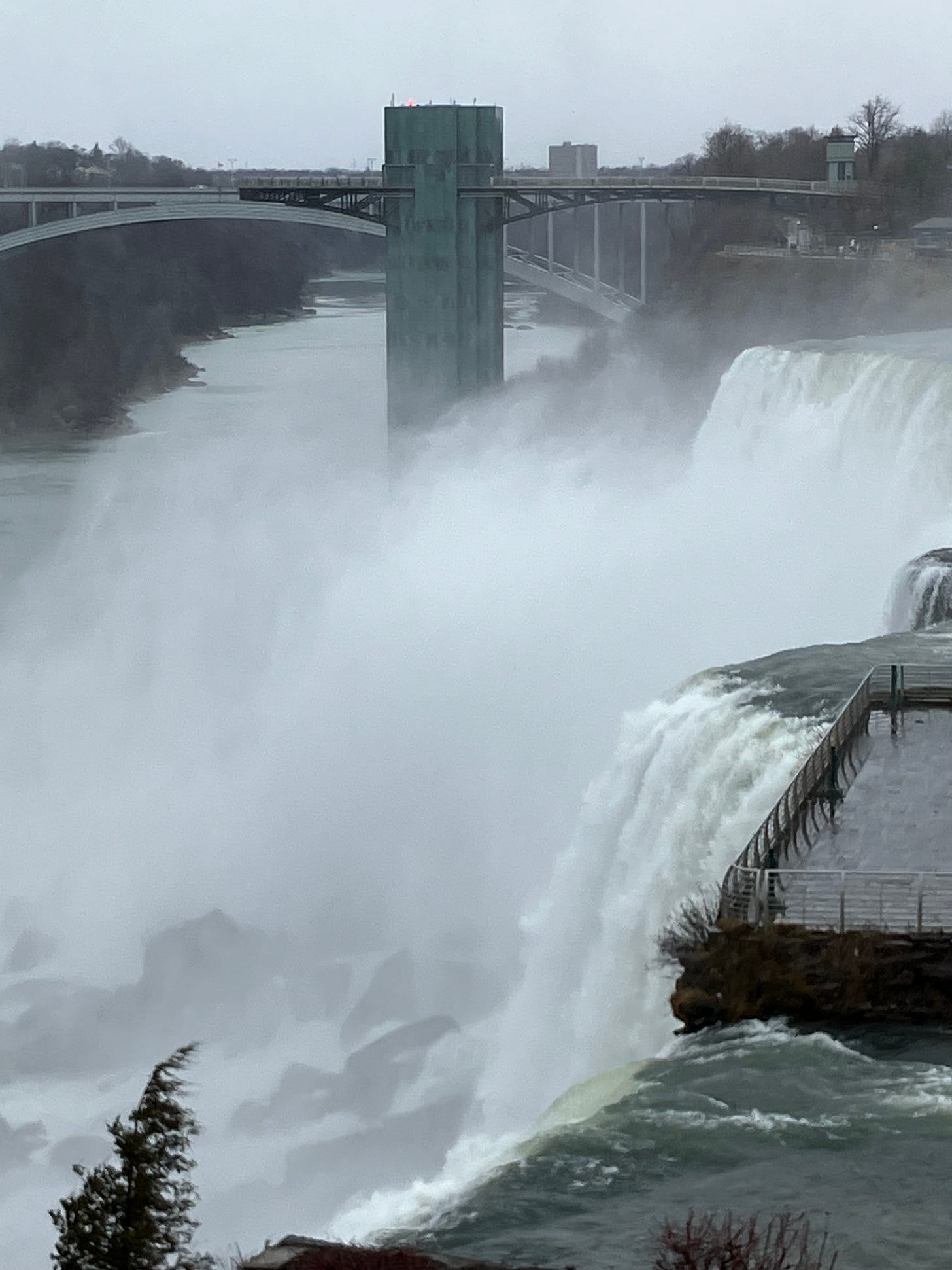 photograph of Niagara River at American Falls with suspension bridge behind rushing water