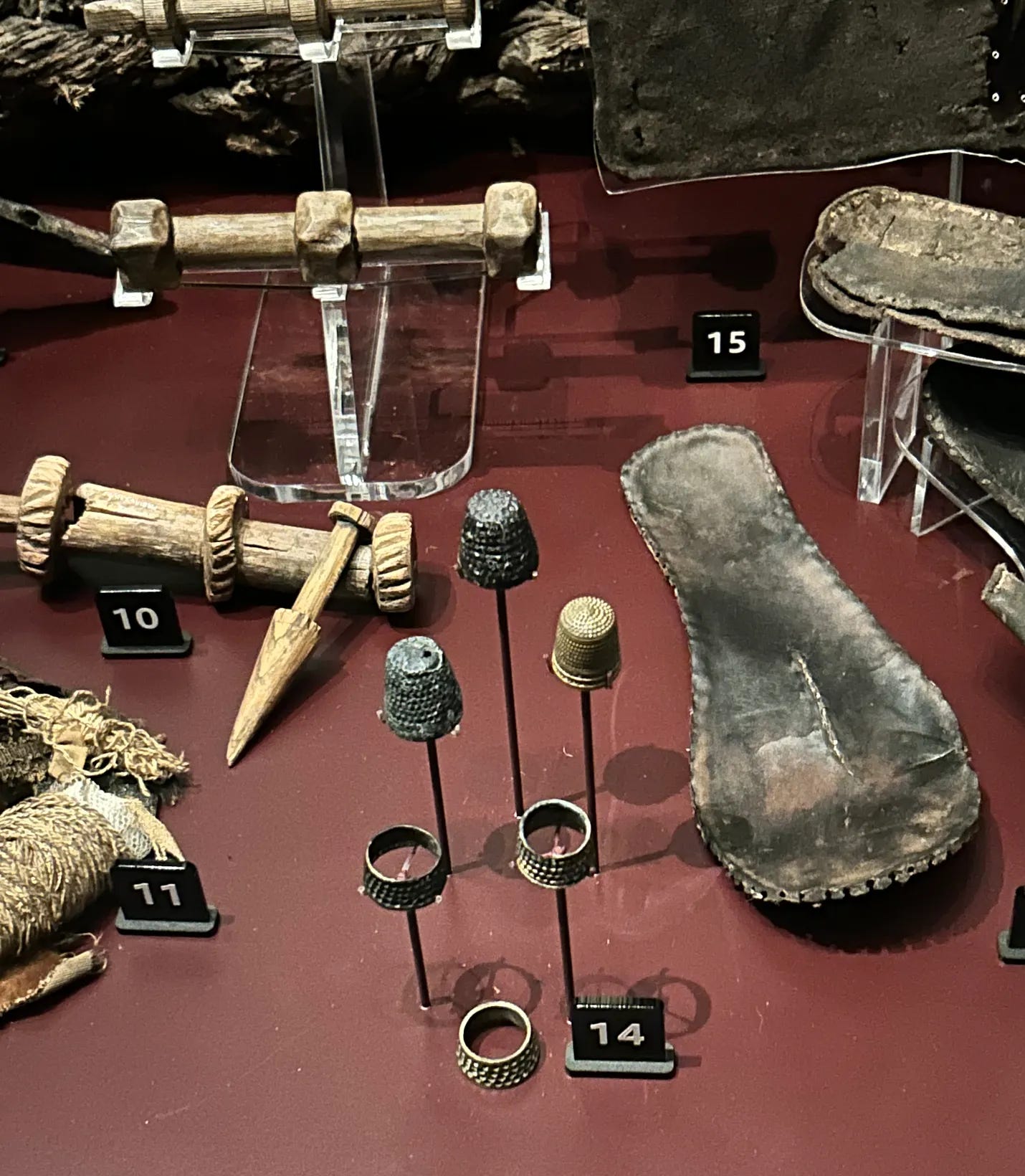 A display of sixteenth century artefacts. There are six thimbles at the front of the display