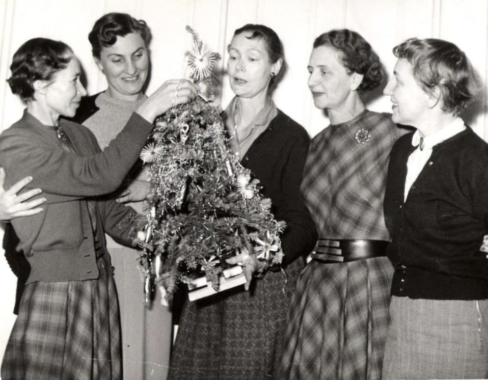 A group of women standing around a christmas tree

Description automatically generated