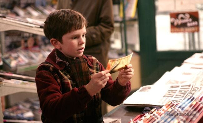 Charlie Bucket examines the Golden Ticket in a candy shop.