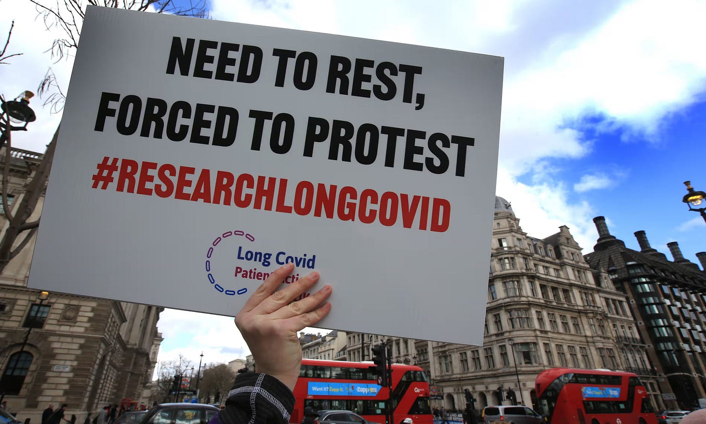 A protester holds up a placard demanding research into long Covid during a demonstration in Parliament Square, London in March 2022. It says, Need to rest, forced to protest. Hashtag research long covid.
