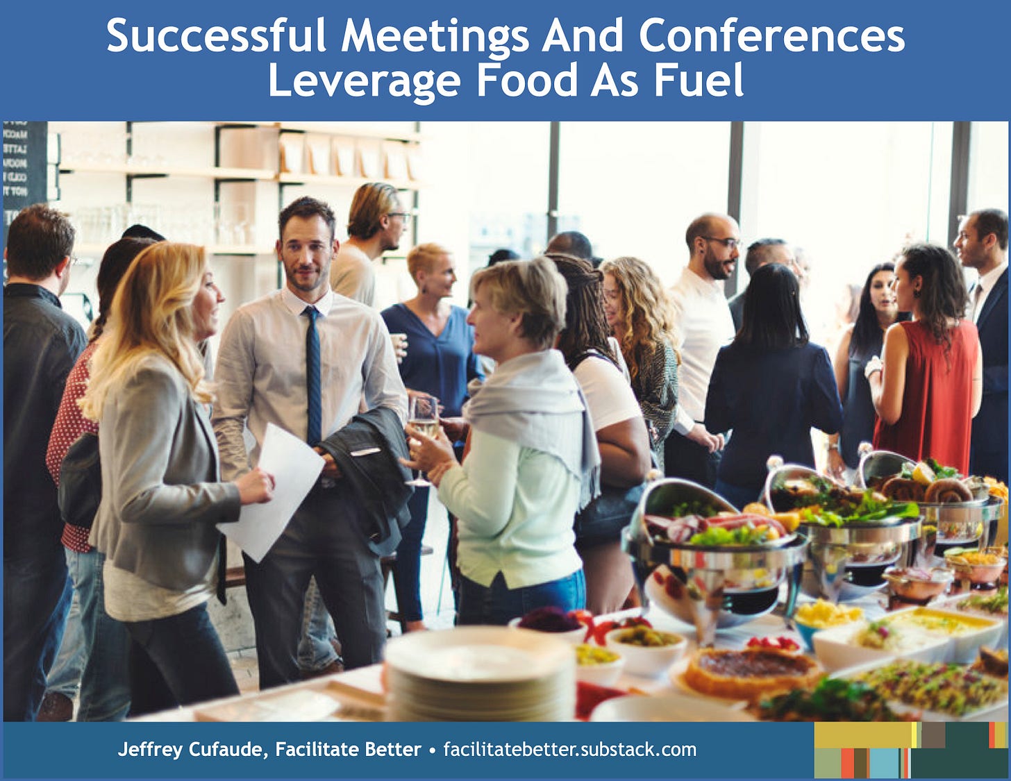 Approximately 15 demographically diverse individuals at a meeting or conference meal function stand in small groups, conversing with each other adjacent to a food buffet.