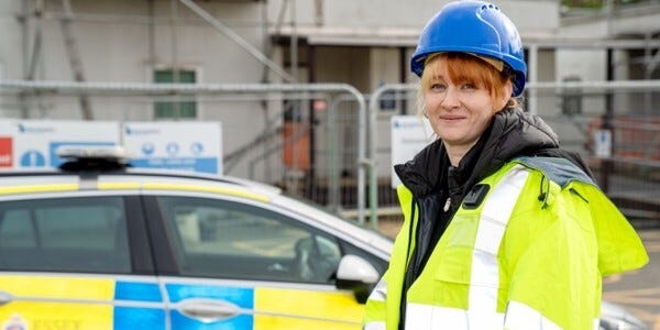 Project Manager for Estates Services, Danni Hammond in a blue hard hat on a building site next to a police car