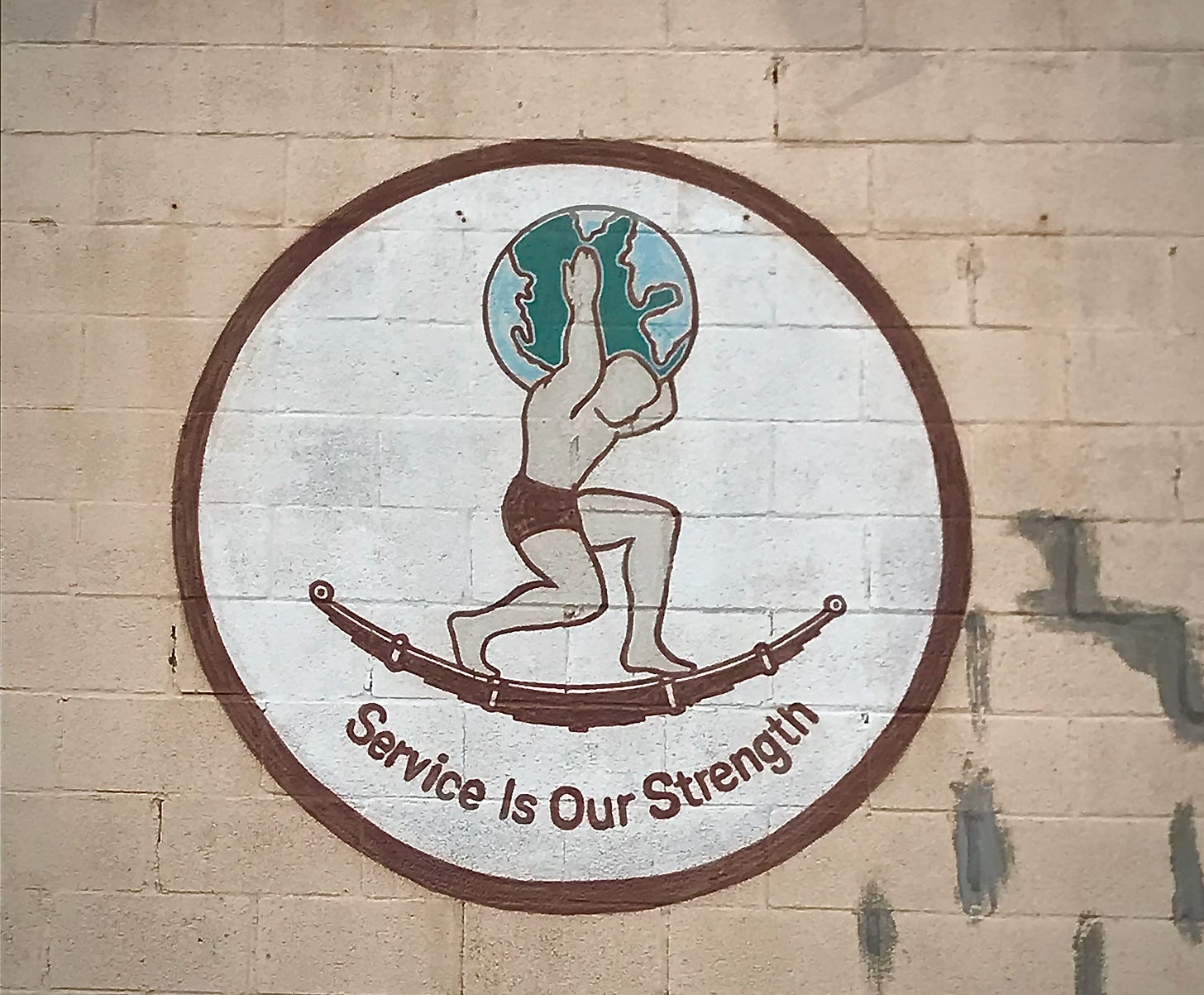 Painted logo of Atlas holding up the world while standing on truck springs, with the motto "Service Is Our Strength."