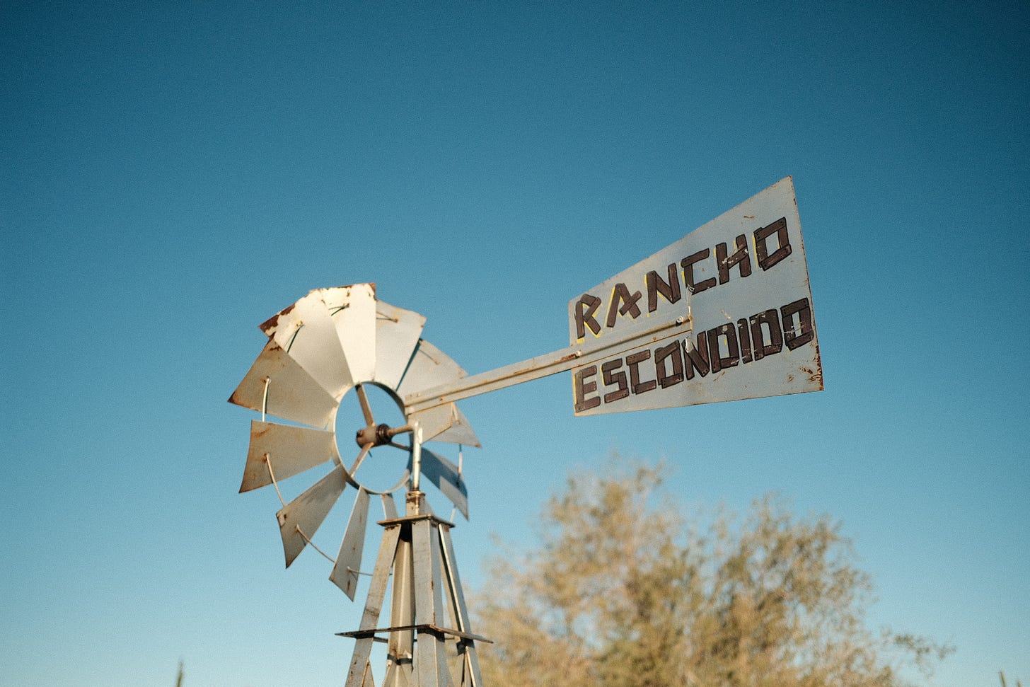 A metal windmill water pump with a sign marking the name Rancho Escondido